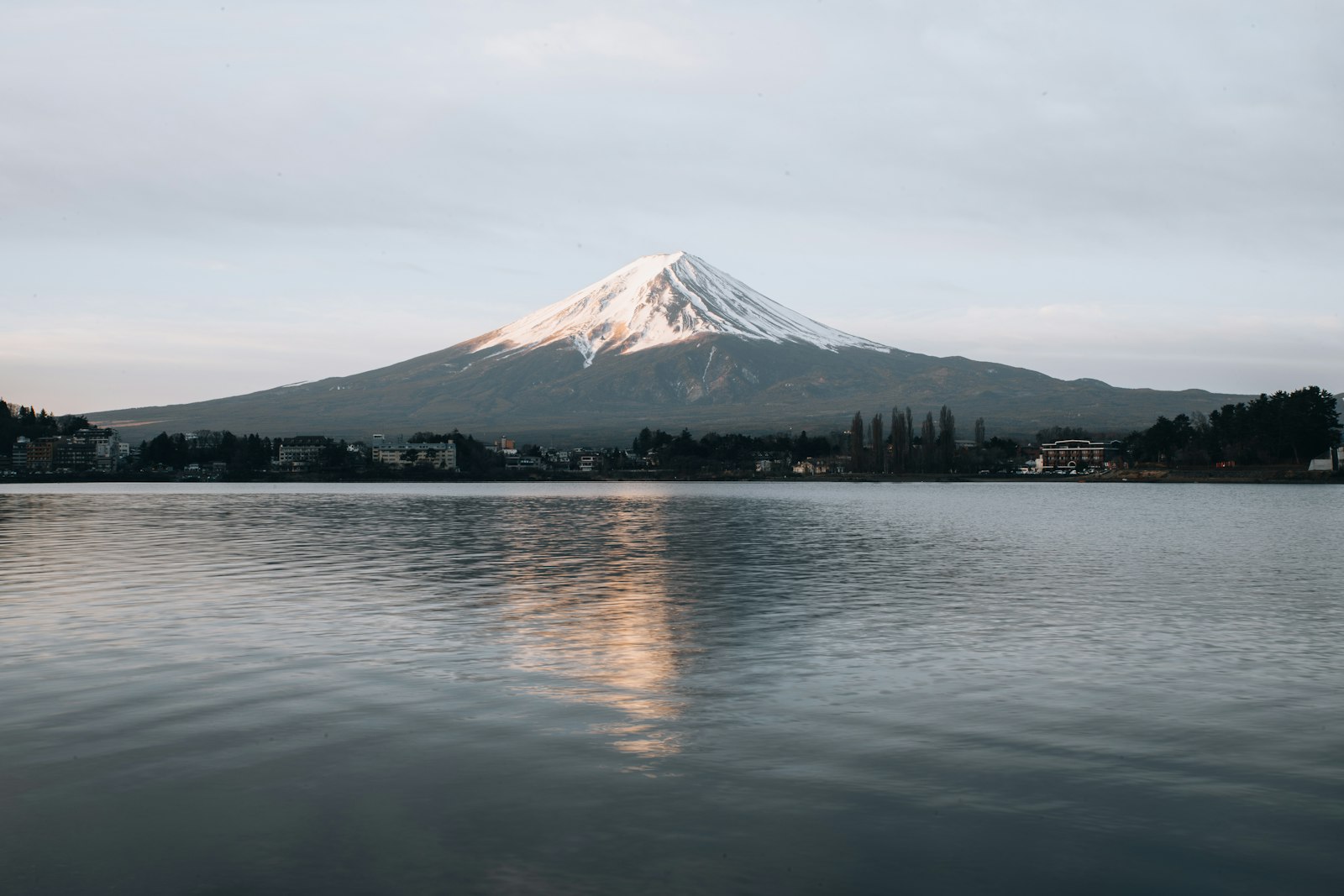 Besneeuwde top van Mount Fuji boven een meer in de ochtend